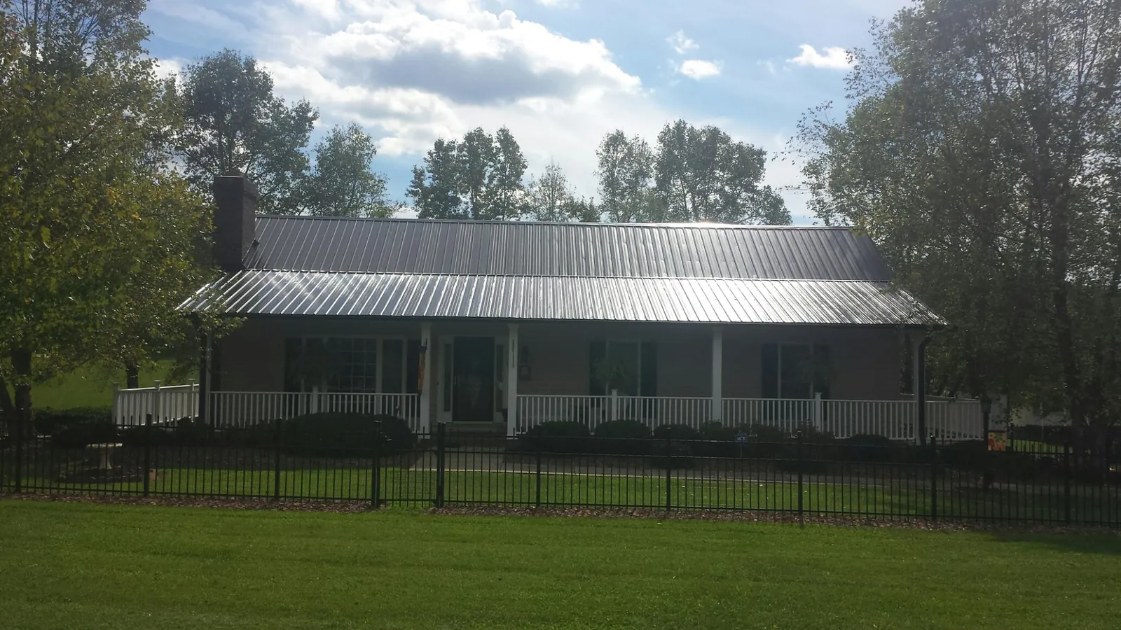 Gray metal roof on a brick ranch with a full width front porch — Gutter Guard Installation work by our crew in Grover